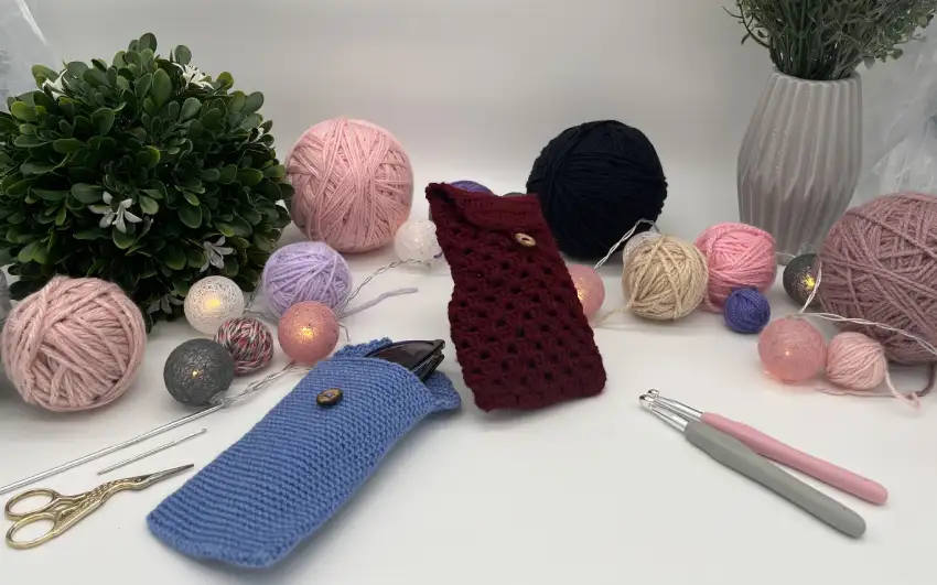 Zwei Brillenetuis mit Garn und Häkelnadel arrangiert.