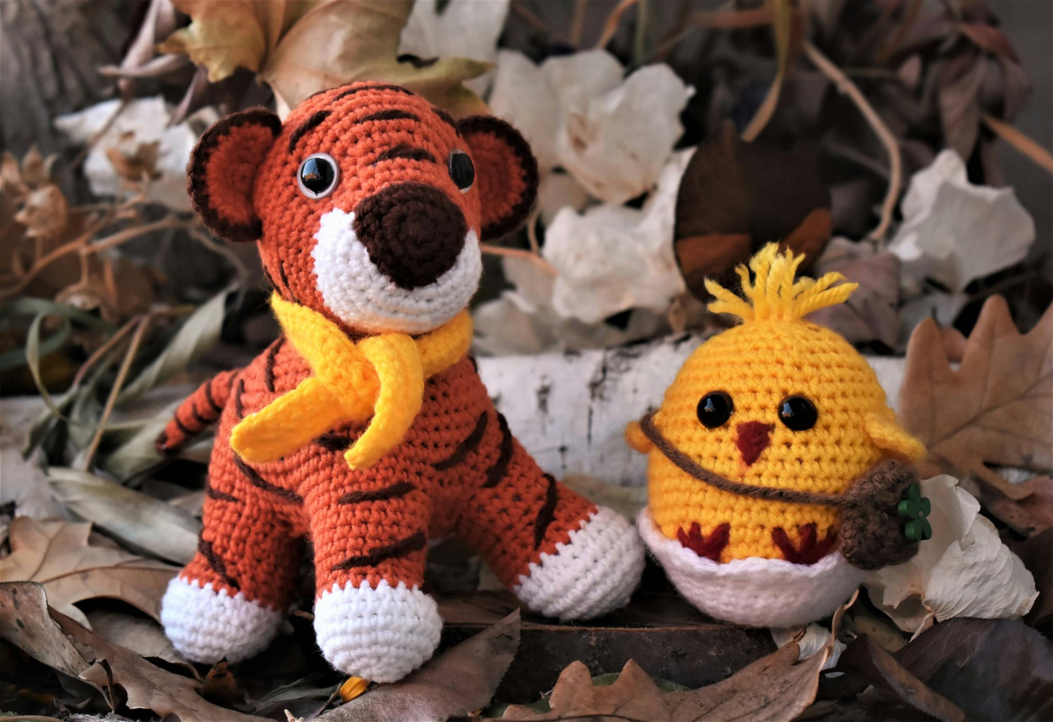 Crochet stuffed tiger and chick among autumn leaves, perfect for seasonal decor.