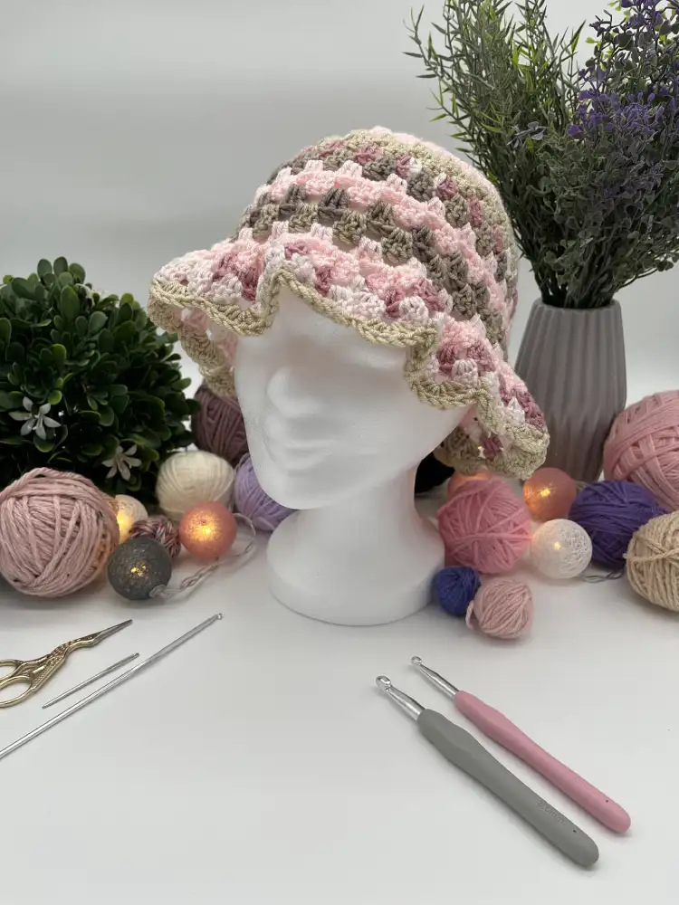 Bunter Bucket Hat auf weißem Modellkopf mit Garnarrangement.