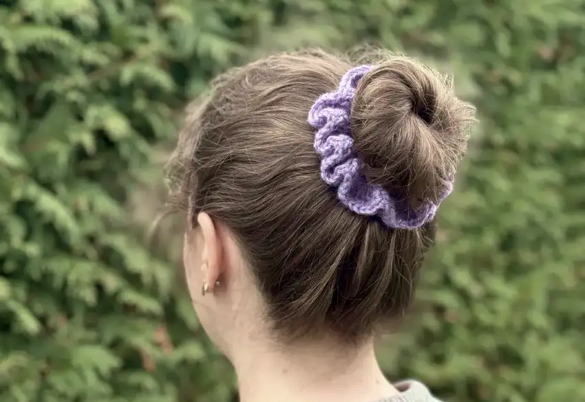 Frau mit lilafarbenem gehäkeltem Haargummi im Haar.