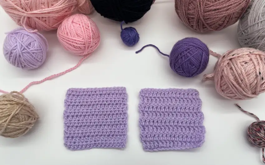 Zwei gehäkelte Probestücke und viele Wollknäuel.