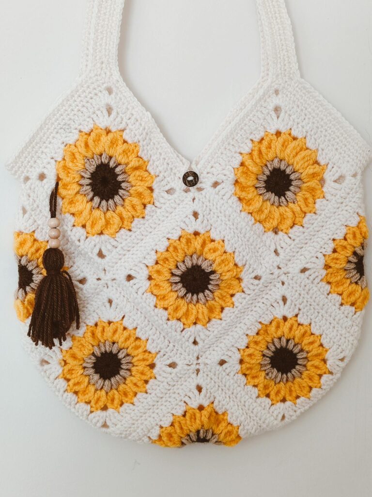 Handcrafted crochet tote bag with sunflower design and tassel accent.