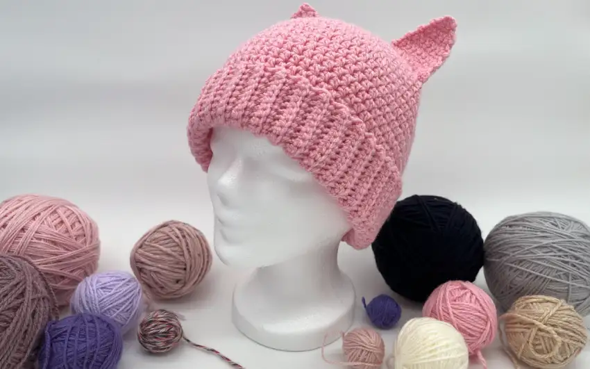 Rosa Mütze mit Katzenohren auf Styroporkopf mit Deko.