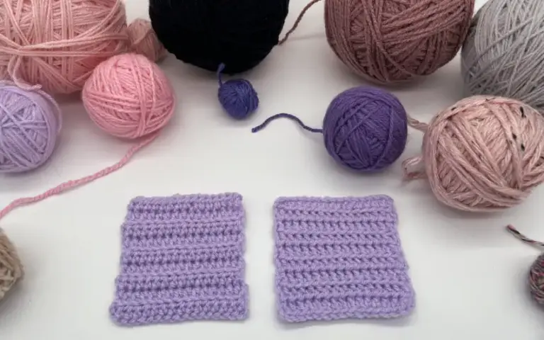 Gehäkelte lilafarbene Probe mit Wolle auf weißem Hintergrund.